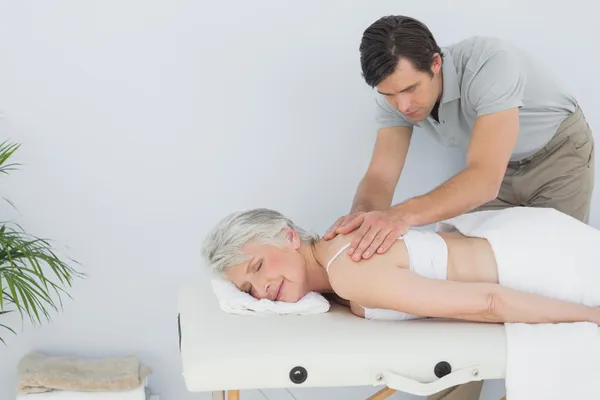 Fisioterapeuta do sexo masculino massageando as costas de uma mulher idosa — Fotografia de Stock
