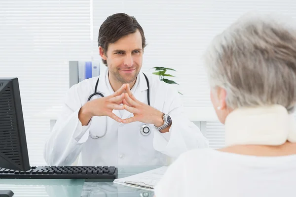 Médico sonriente escuchando a un paciente mayor en el consultorio médico — Foto de Stock