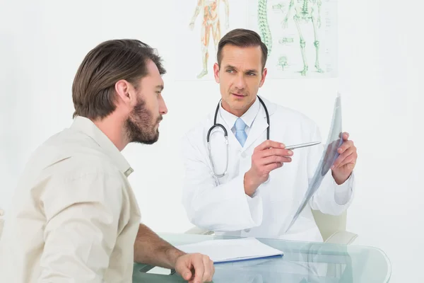 Male doctor explaining spine x-ray to patient