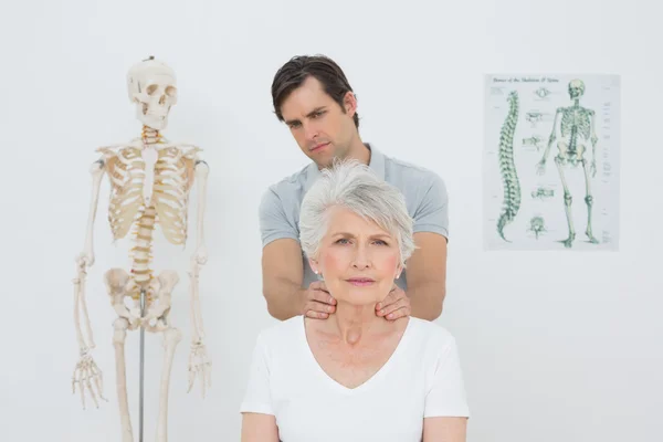 Fisioterapeuta masajeando el cuello de una mujer mayor — Foto de Stock