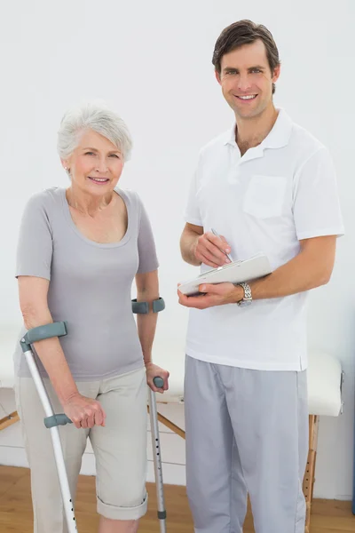Therapist and disabled senior patient with reports — Stock Photo, Image