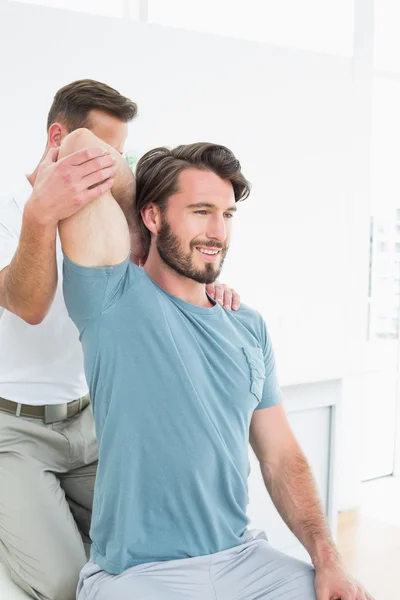 Fisioterapeuta masculino estirando el brazo de un joven —  Fotos de Stock