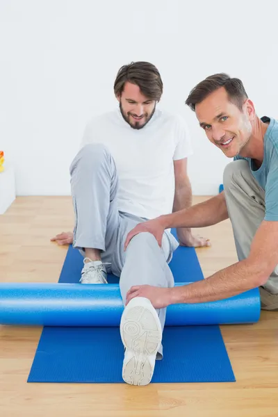 Fisioterapeuta examinando la pierna de un joven — Foto de Stock