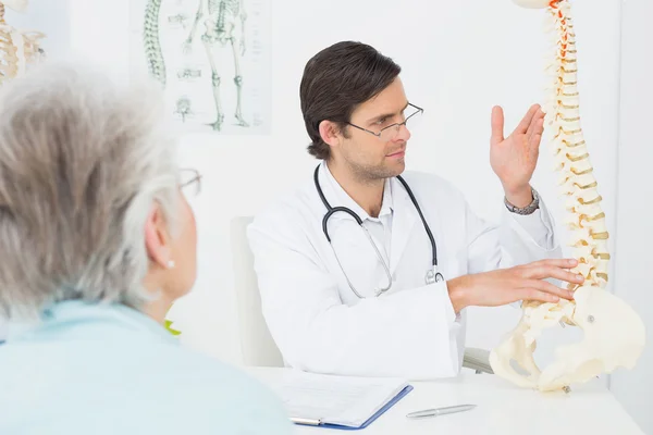 Médecin homme expliquant la colonne vertébrale à un patient âgé — Photo