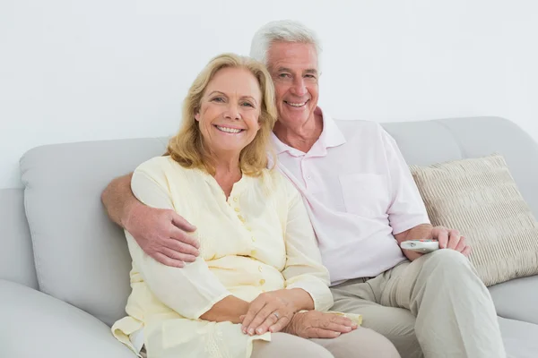 Relaxed happy senior couple with remote control at home — Stock Photo, Image