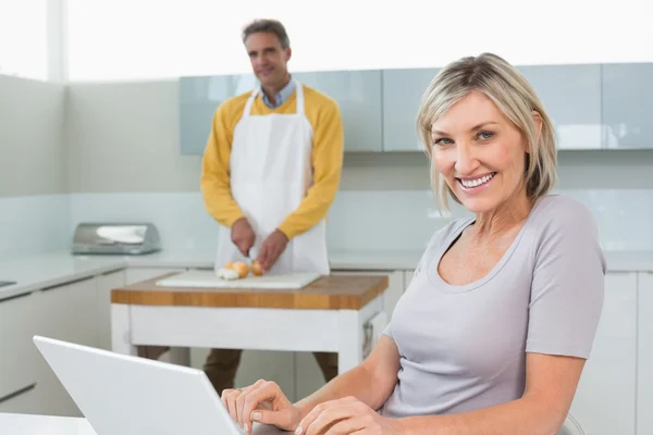 Vrouw met laptop en man hakken groenten — Stockfoto