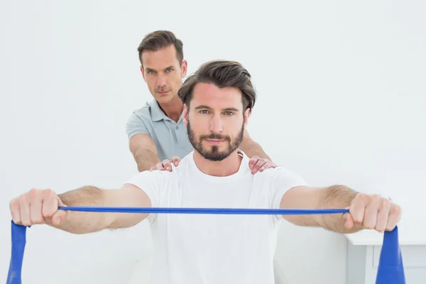 Male therapist assisting a young man with exercises — Stock Photo, Image
