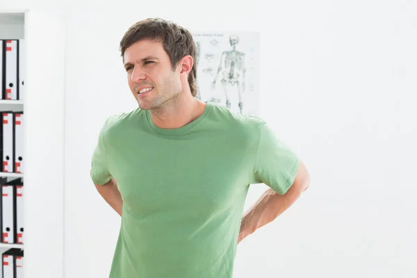 Portrait of a handsome young man with back pain — Stock Photo, Image