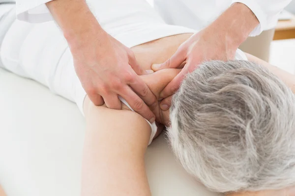 Fisioterapeuta masajeando la espalda de una mujer mayor — Foto de Stock