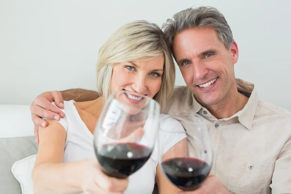 Couple holding out wine glasses at home — Stock Photo, Image