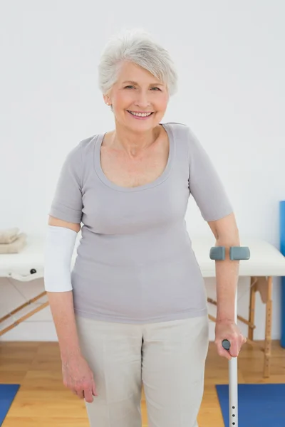 Portrait of a smiling senior woman with crutch — Stock Photo, Image