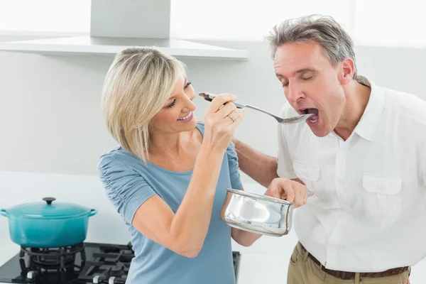 Mujer cariñosa alimentando a un hombre en la cocina — Foto de Stock