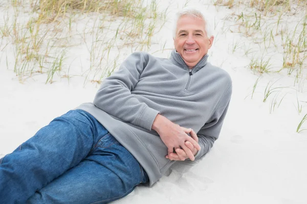 Smiling senior man relaxing on sand at beach — Stock Photo, Image