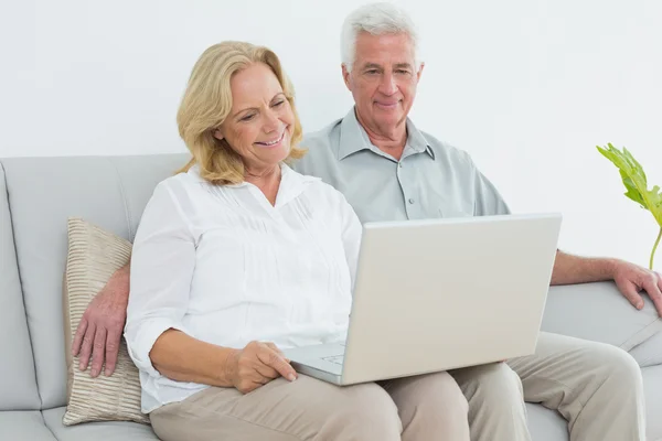 Avslappnad äldre par med laptop på house — Stockfoto