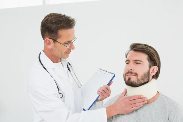 Mężczyzna lekarz bada pacjenta skręconą szyję — Zdjęcie stockowe