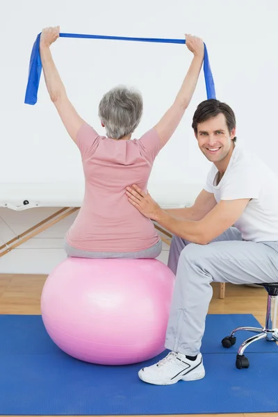 Senior woman on yoga ball with a physical therapist — Stock Photo, Image