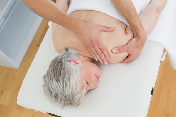 Fisioterapeuta masajeando la espalda de una mujer mayor — Foto de Stock