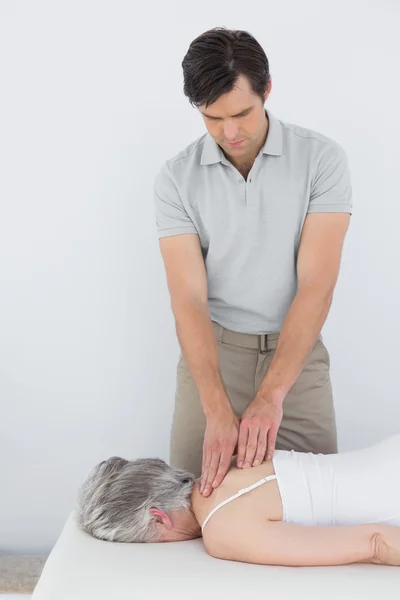 Fisioterapeuta masculino masajeando la espalda de una mujer mayor — Foto de Stock