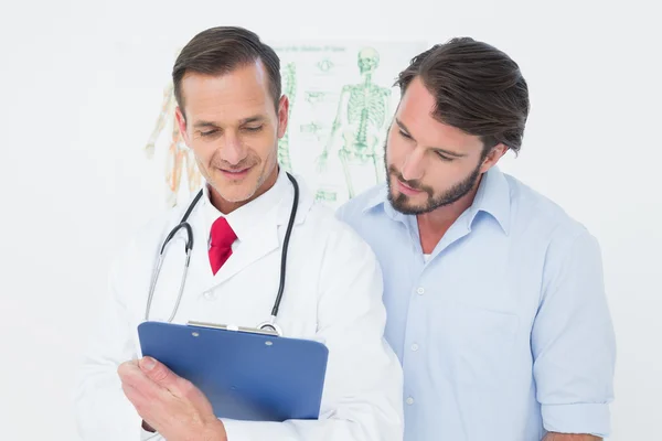 Male doctor discussing reports with patient — Stock Photo, Image