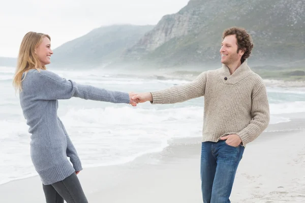 Lyckliga paret håller händerna på stranden — Stockfoto