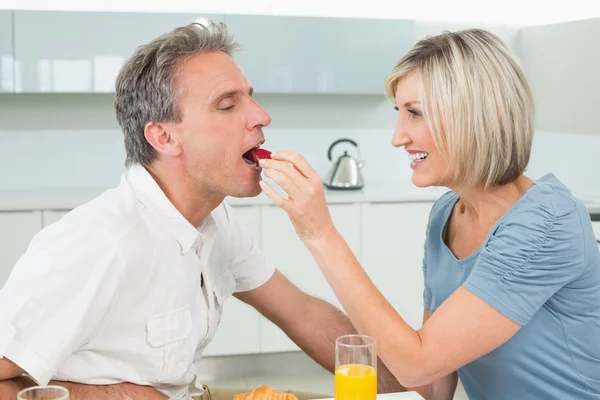 Loving woman feeding man in the kitchen — Stock Photo, Image