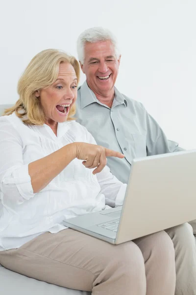 开朗的年长夫妇在家里使用便携式计算机 — 图库照片