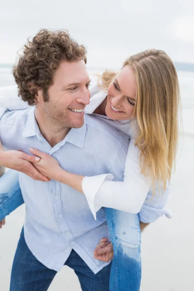 Uomo piggybacking donna in spiaggia — Foto Stock