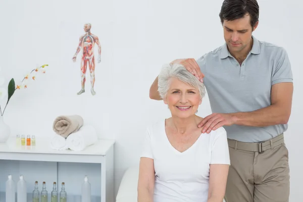 Senior vrouw de nek aanpassing gedaan krijgen — Stockfoto