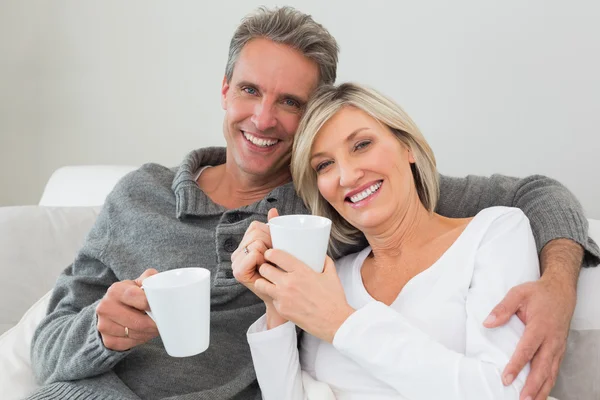 Relajada pareja feliz con tazas de café en la sala de estar — Foto de Stock