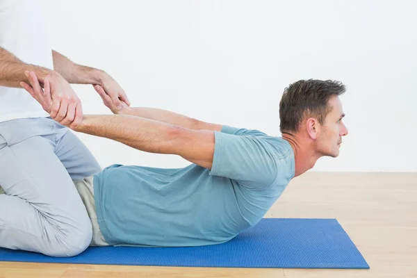 Fisioterapeuta que ayuda al hombre con ejercicios de estiramiento — Foto de Stock
