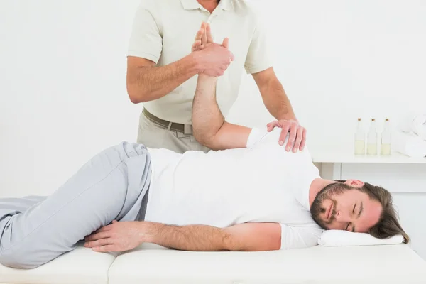 Mužské fyzioterapeut zkoumání mladý muži ruku — Stock fotografie