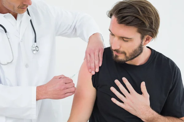 Male doctor injecting a young male patient's arm — Stock Photo, Image