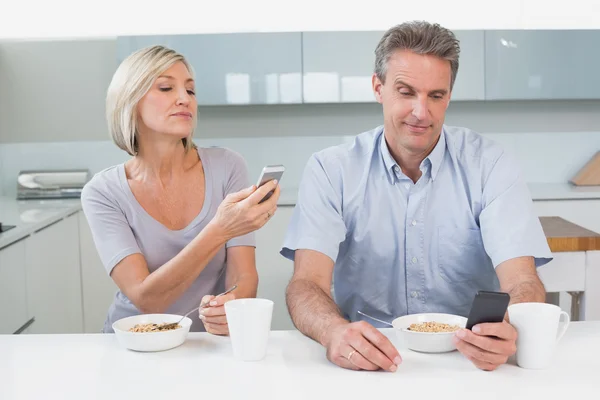 Casal ler mensagens de texto enquanto toma café da manhã — Fotografia de Stock