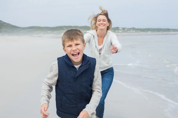 Женщина и веселый мальчик бегают по пляжу — стоковое фото