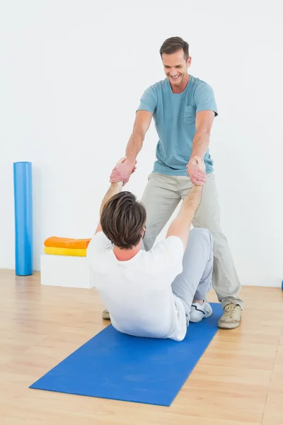 Мужской терапевт помогает человеку с упражнениями на растяжку — стоковое фото