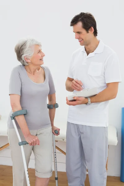 Therapist discussing reports with a disabled senior patient — Stock Photo, Image