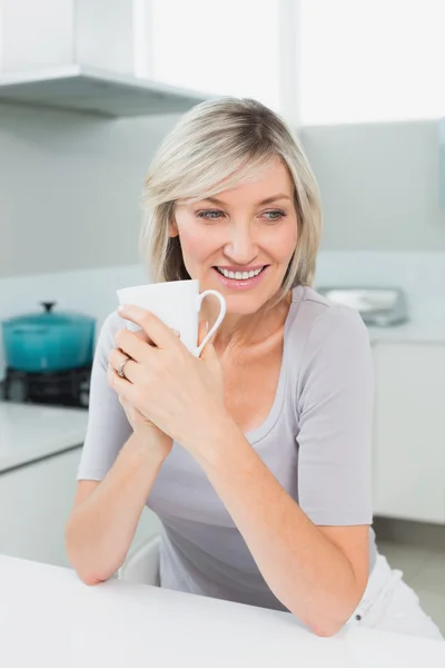 Doordachte lachende vrouw met koffie beker in keuken — Stockfoto