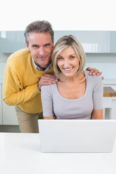 Retrato de una pareja feliz con portátil en la cocina — Foto de Stock