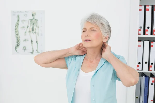 Senior woman suffering from neck pain in medical office — Stock Photo, Image