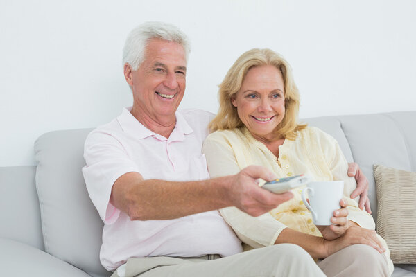 Cheerful senior couple watching television