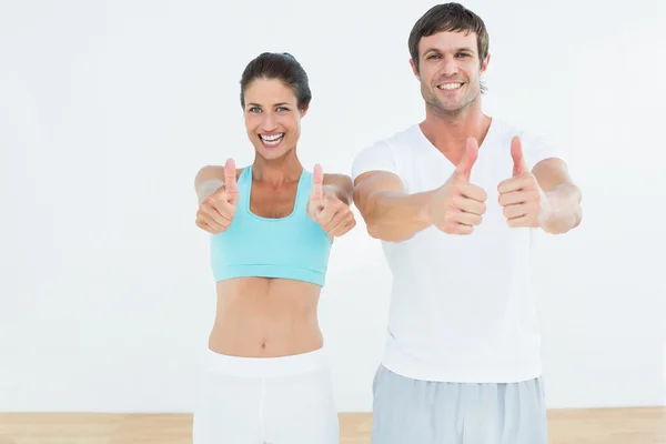 Gelukkig passen paar gebaren duimen omhoog in de fitness-studio — Stockfoto