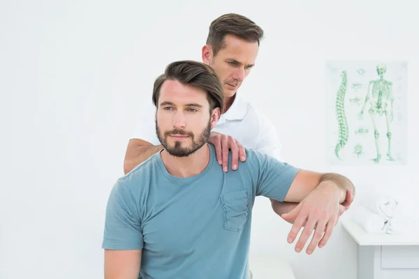 Fisioterapeuta masculino esticando o braço de um jovem — Fotografia de Stock