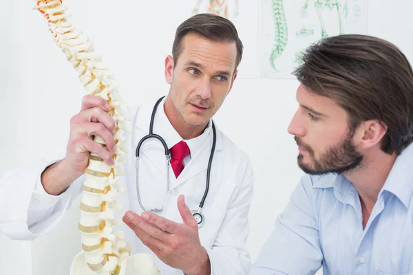 Médico varón explicando la columna vertebral a un paciente — Foto de Stock