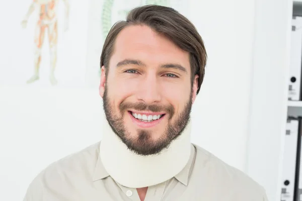 Портрет улыбающегося молодого человека в хирургическом воротнике — стоковое фото