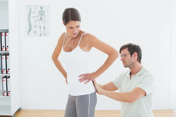 Fisioterapeuta examinando la espalda de la mujer en el consultorio médico — Foto de Stock