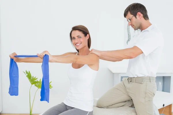 Male therapist assisting young woman with exercises — Stock Photo, Image