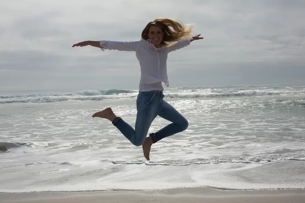 Hela längden av en casual kvinna hoppa på stranden — Stockfoto
