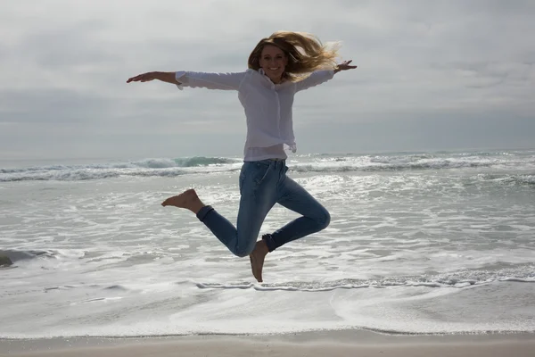 Volledige lengte van een toevallige vrouw springen op strand — Stockfoto