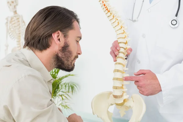 Médico masculino explicando a coluna vertebral a um paciente — Fotografia de Stock