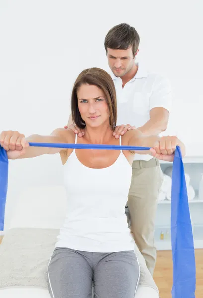 Terapeuta masculino que ayuda a la mujer joven con ejercicios — Foto de Stock